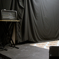 Pic of showcase room stage with PA, floor monitors, microphones on stands, and lighting
